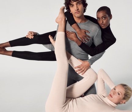 Drei Personen in schlichten, enganliegenden Seidenoutfits posieren kunstvoll. Die Kleidung symbolisiert Eleganz und Komfort – ideal für Tipps zum Seide waschen.