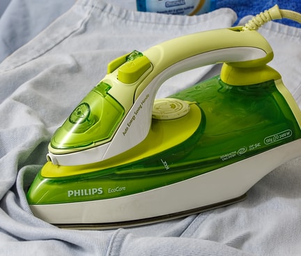 Ein grünes Philips-Bügeleisen auf einem Kleidungsstück – Tipps und Techniken für richtiges Bügeln leicht gemacht.