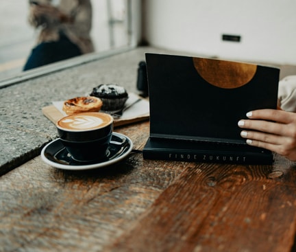 Digital Detox im Café – Person mit Buch und Kaffee, ohne digitale Ablenkung.