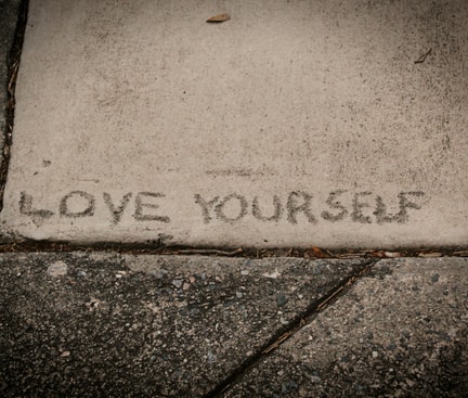 In den Beton eingravierter Schriftzug 'LOVE YOURSELF' – Selbstliebe lernen und sich selbst wertschätzen.