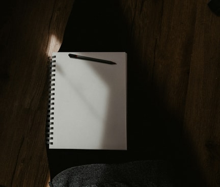 Schlaftagebuch mit Stift liegt auf dem Schoß einer Person.