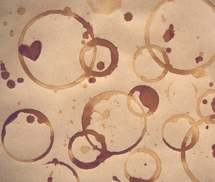 Mehrere braune Kaffeeflecken auf Papier, die den typischen Kaffeeflecken auf Kleidung ähneln.