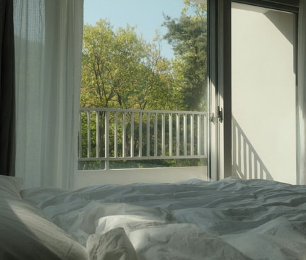 Fenêtre ouverte avec vue sur la verdure – symbole d’aérer avant de dormir pour un meilleur climat intérieur.