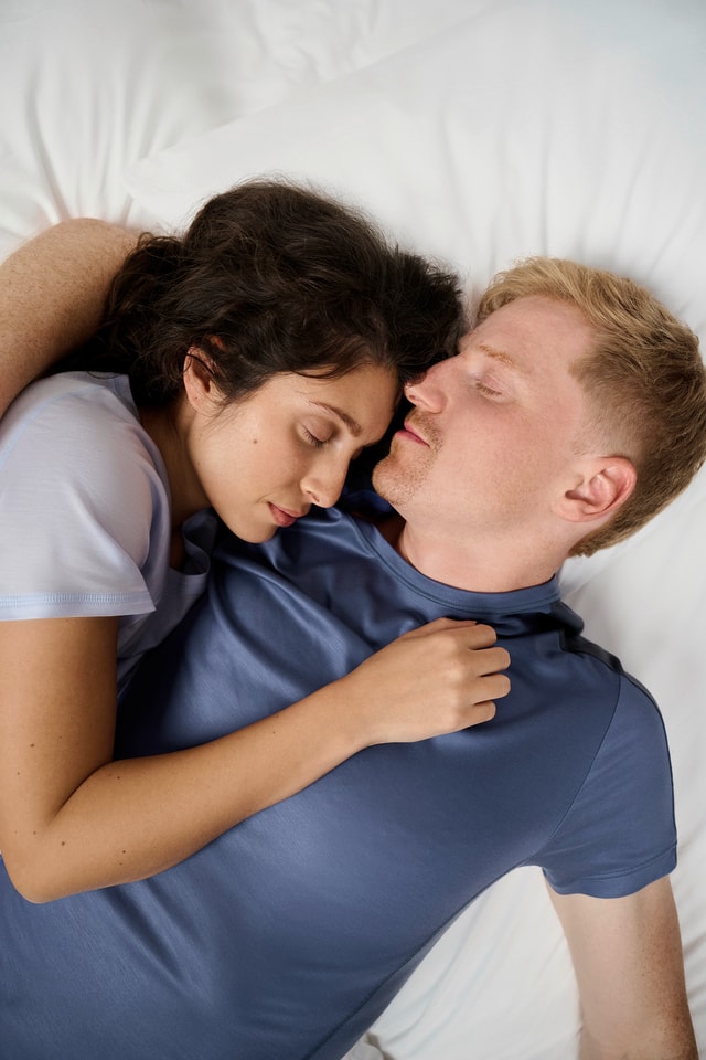 Two people lying closely embraced on a white bed, sleeping – calm and intimate atmosphere