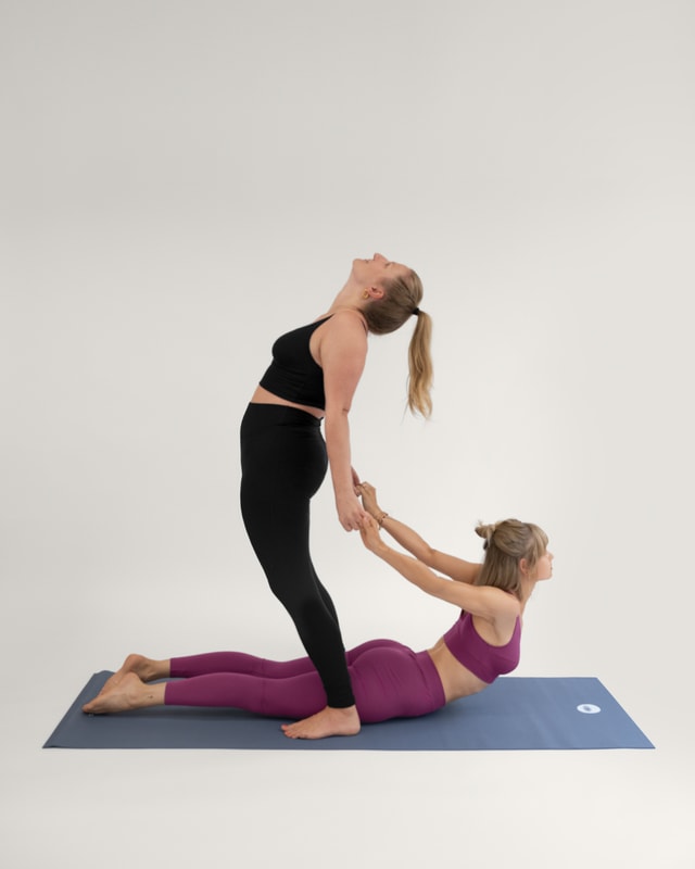 Zwei Frauen in der Yoga-Pose "Die gemeinsame Kobra / Herzöffner" (Bhujangasana).
