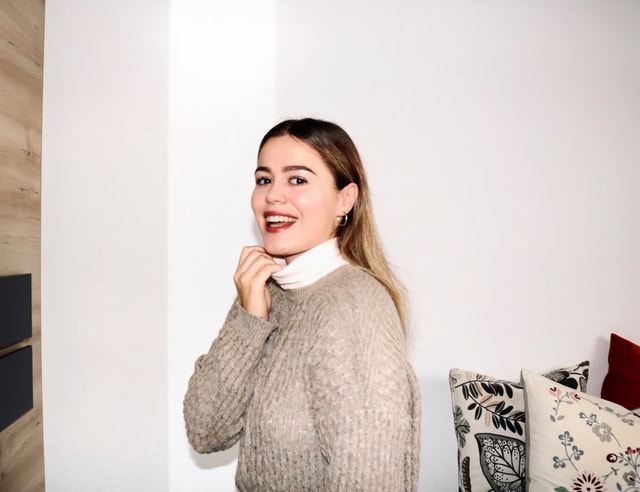 Frau trägt weissen Rollkragenpullover von CALIDA unter einem braunem Strickpullover