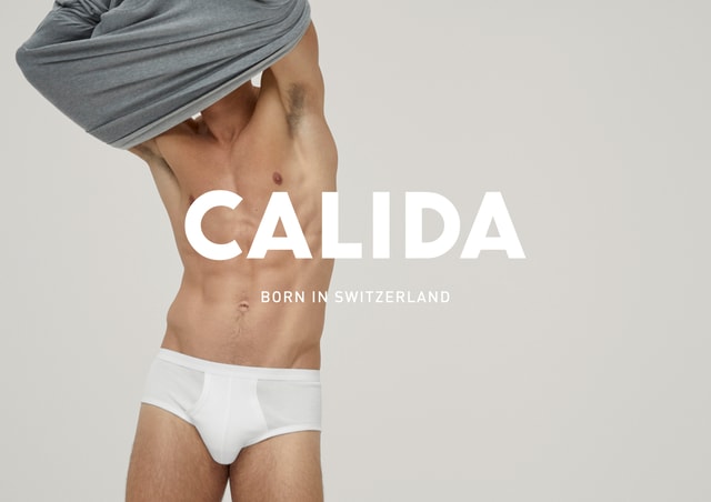 Mann in weißer Unterhose zieht sich sein T-Shirt aus. CALIDA Schriftzug mit dem Untertitel 'Born in Switzerland'.