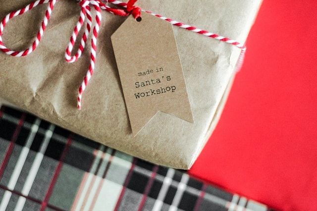 Ein Geschenk mit einem braunen Geschenksanhänger. Auf dem Geschenksanhänger steht in einer schwarzen Schrift: made in Santa's Workshop